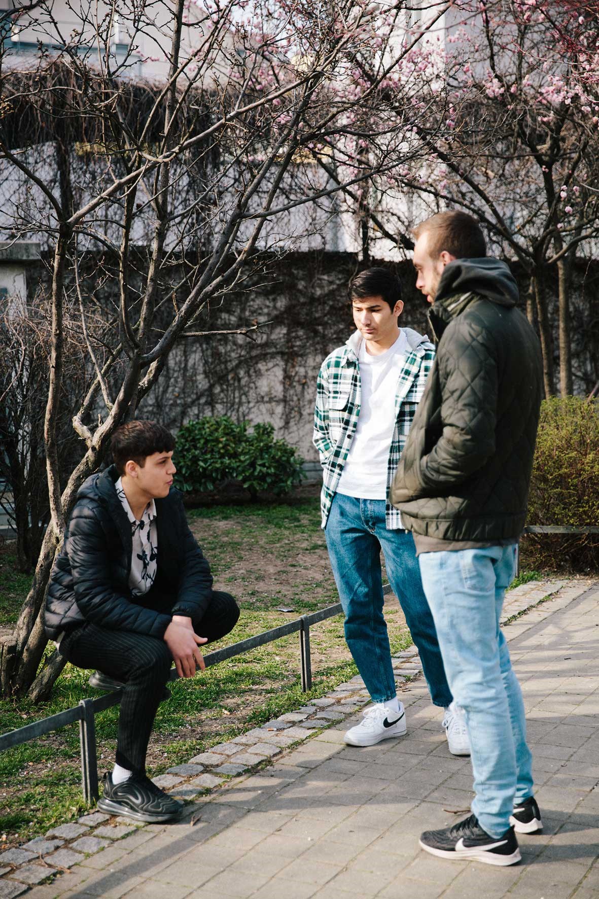 © Caterina Donner Drei junge Männer am Wegrand in einem Park.