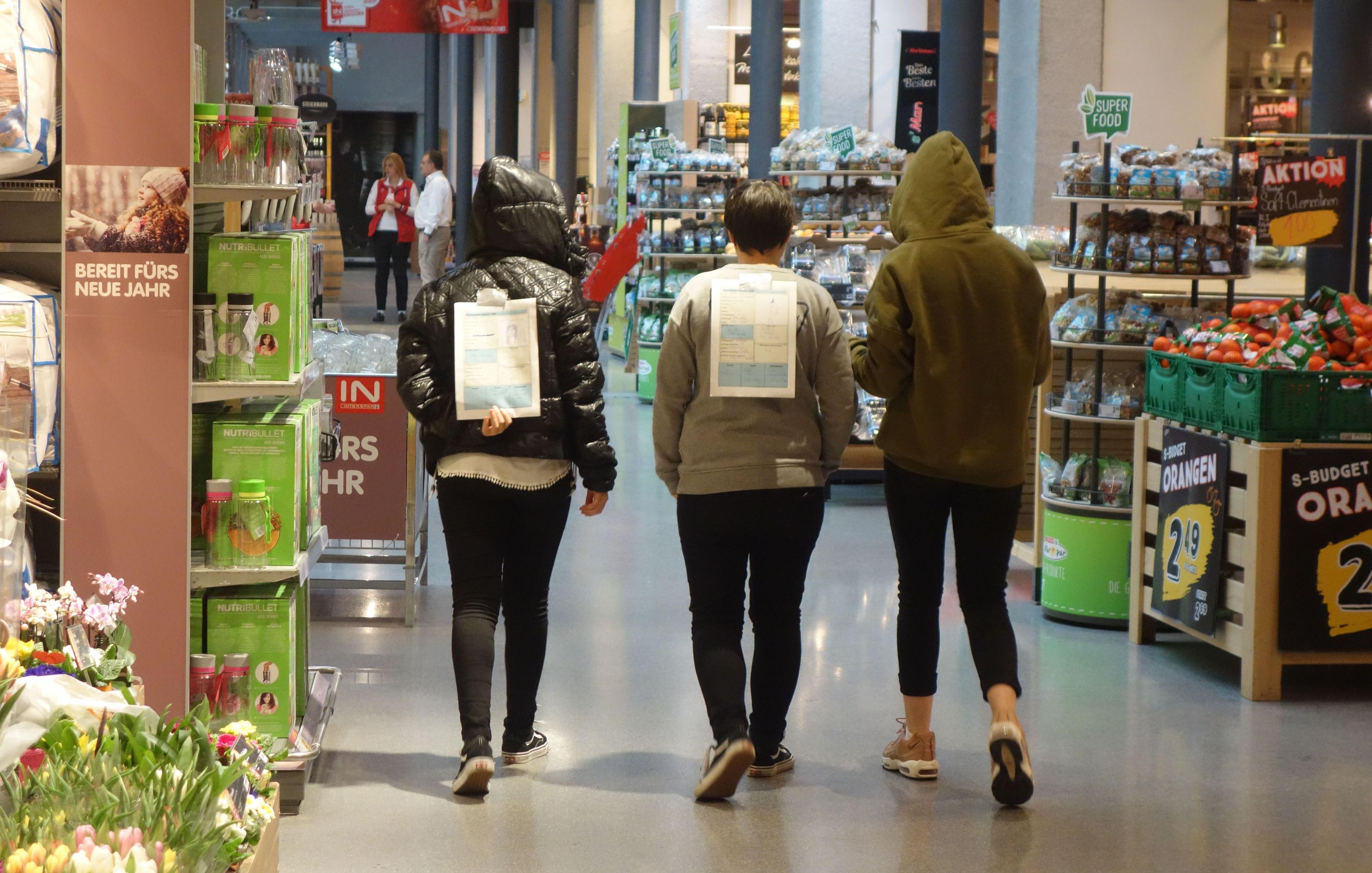 Jugendliche von hinten fotografiert - gehen den Gang eines Einkaufszentrums entlang