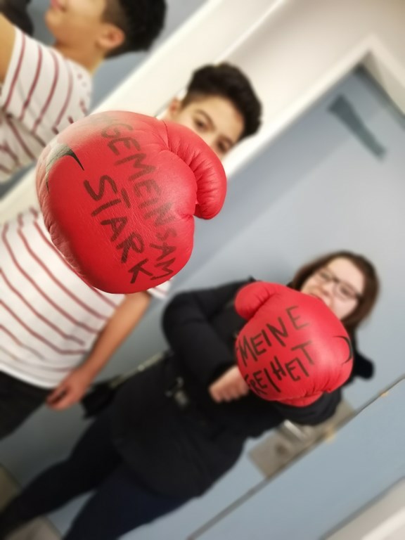 zwei Jugendliche stehen mit roten Boxhandschuhen da, vorauf geschrieben steht: Gemeinsam stark, Freiheit